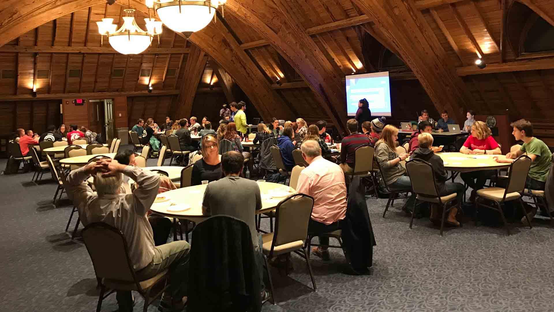 Students, facult and guests sit at tables for trivia night